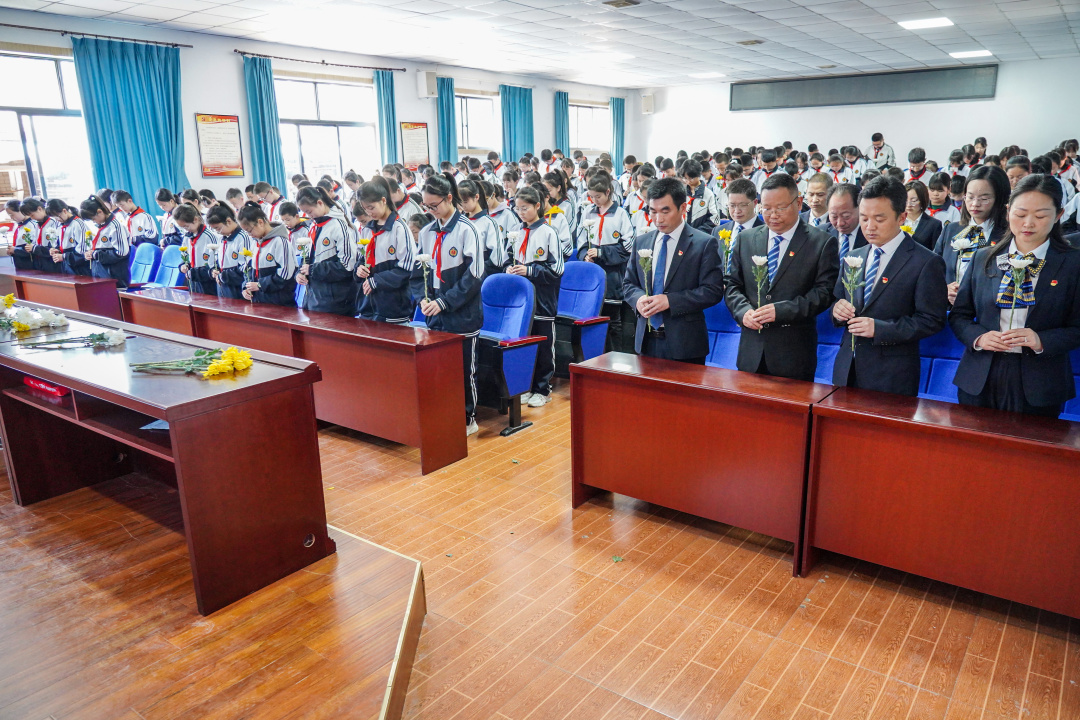 師生們開展網(wǎng)上祭奠活動，手拿鮮花面對大屏幕低頭默哀。.jpg