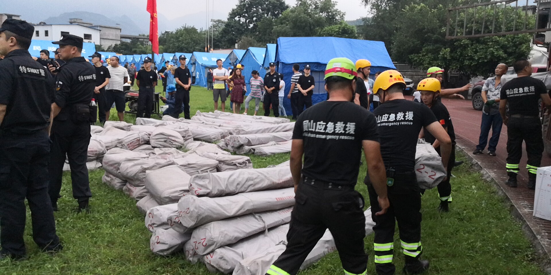 18日晚7時20分左右，救援隊員和武警官兵冒雨為群眾搬運救災帳篷。2.jpg