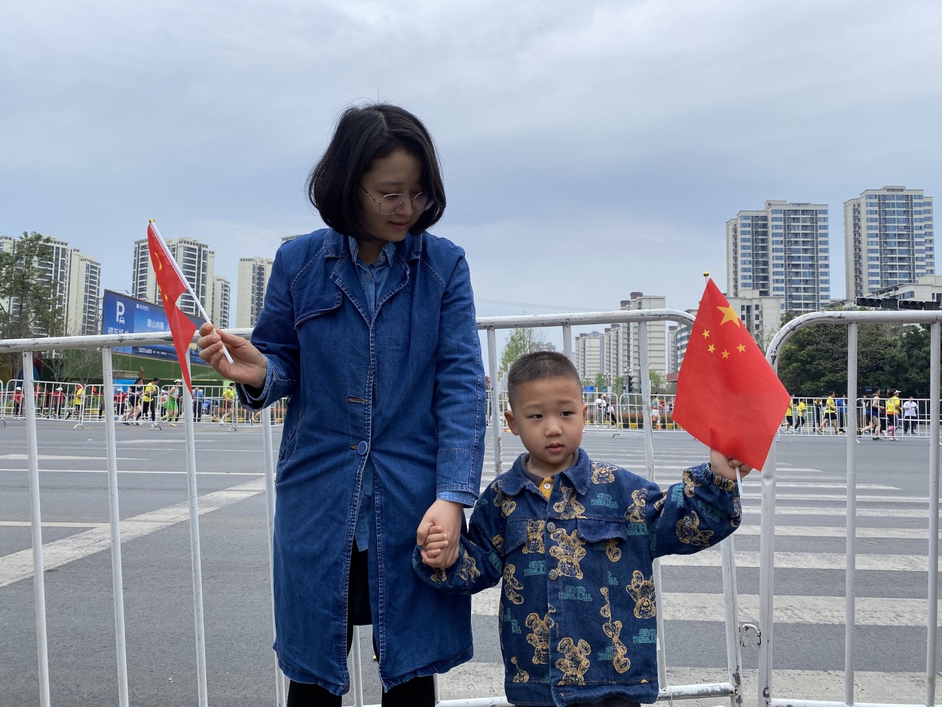 東坡大道與齊通路路口，一對母子揮舞五星紅旗為參賽選手加油鼓勁。.jpg